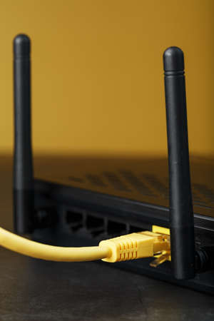 A yellow patch cord is inserted into the WiFi port of the router to access the Internet. Internet connection via a wire with a router. Macro, close-upの写真素材