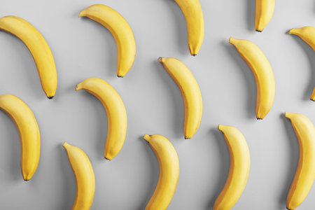 Geometric pattern of bananas on a gray background. The view from the top. Minimal flat style. Pop art design, creative summer concept.の写真素材
