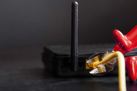 Disconnecting the Internet connection, cutting off the yellow  cable with wire cutters with a red handle on the WiFi router. Disconnecting from the global Internetの写真素材