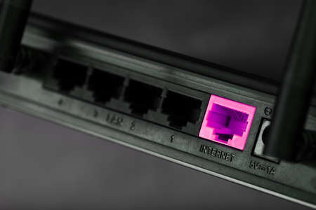 A pink patch cord is inserted into the router's WiFi port to access the Internet.の写真素材