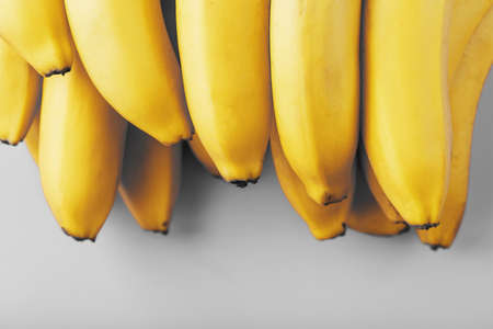 A bunch of fresh yellow bananas on a gray background in the fashionable colors of 2021. Top View. Minimalistic concept. Free space.の写真素材