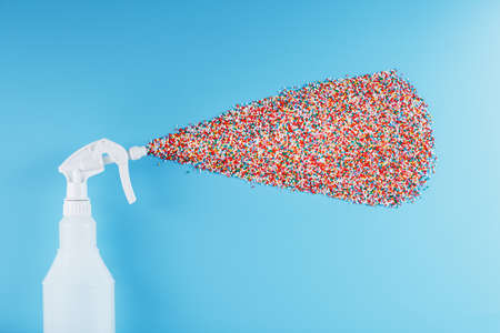 The spray sprays colorful nonpareil balls on a blue background. Isolate, top view. The concept of rainbow and non-standard splashesの写真素材