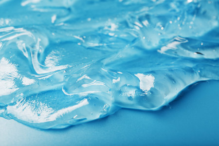 Gel with hyaluronic acid in the form of a smear of glossy texture on a blue background....