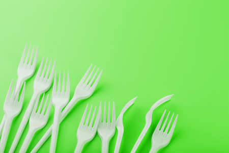 Plastic dishes on a green background with free space. Plastic waste separation and collection concept. Refusal from plasticの写真素材