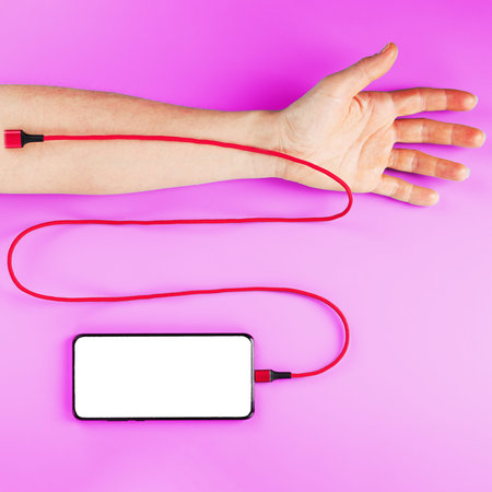 A smartphone with a large white screen is connected via a red USB cord to a vein in the hand on a...
