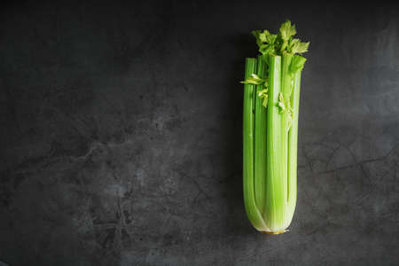 Green stalks of celery on a black stone background. Top view, free spaceの写真素材