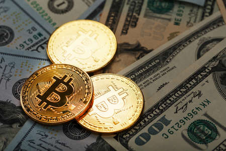 Gold bitcoin coins on the background of dollar billsの写真素材