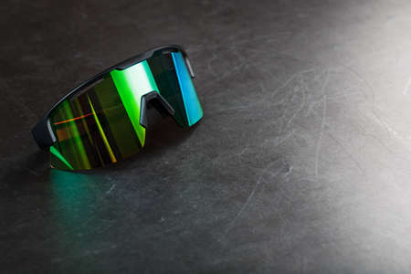 Sports glasses with a green mirrored lens on a black textured background. Free space.の写真素材