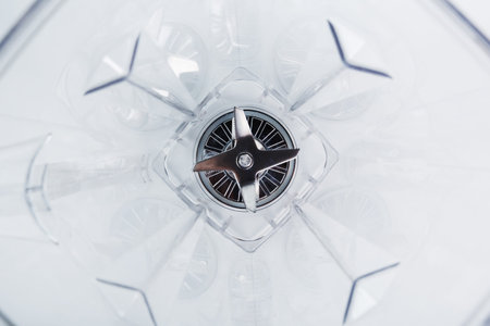 Close-up of a blender glass shot from the inside with sharp stainless steel blades in the center....