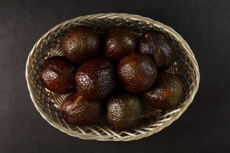 Ripe Hass Avocado in a basket on a black textured background. Top view, free spaceの写真素材