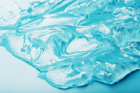 Gel with hyaluronic acid in the form of a smear of glossy texture on a cyan background....