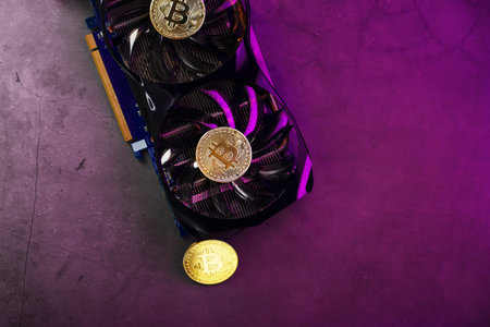 Gold Bitcoin on the video card cooler on a dark background top view. The concept of mining and...