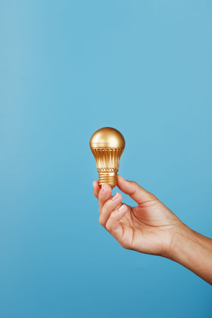 Gold light bulb as an idea in a female hand on a blue background. Isolateの写真素材