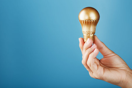 Gold light bulb in hand on a blue background, as a concept of ideas and assistance. Isolate,...