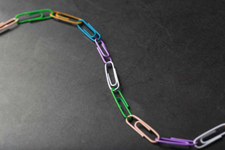 Multi-colored paper clips with a chain on a black background. Business communication and cooperation conceptの写真素材