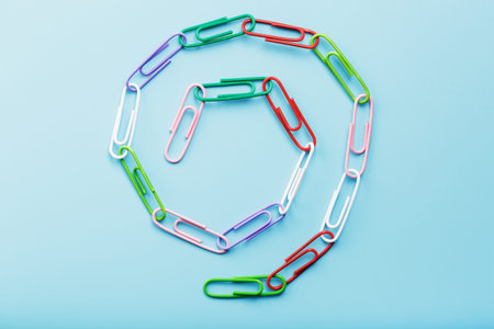 A chain of multi-colored paper clips on a blue background. Business communication and cooperation...