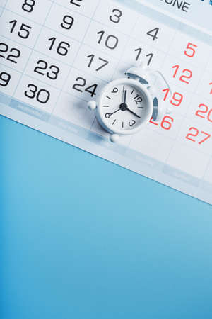 Alarm clock and calendar on a blue background.の写真素材