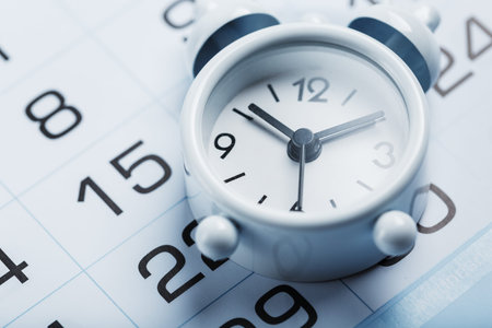 Annual calendar with a white alarm clock on a blue background. The concept of the passage of time...
