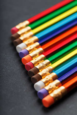Multi-colored pencils for drawing and drawing in a row on a textured black background in a row. Top view, free spaceの写真素材