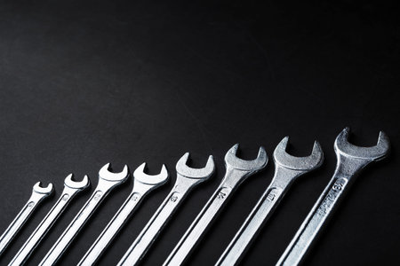 Tool wrenches in a row on a black background with free space. Top view