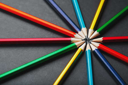 Wooden pencils of different colors in the shape of a star on a black background. Top viewの写真素材