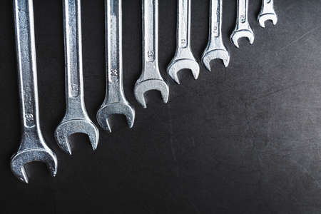 A set of wrenches on a textured black background in a row. Top view, free spaceの写真素材