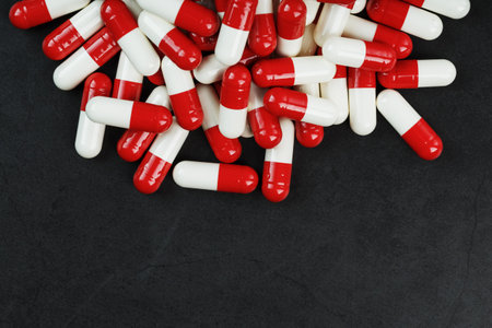 Pills with drugs are scattered on a black background. that is a dosed solid dosage form for oral...