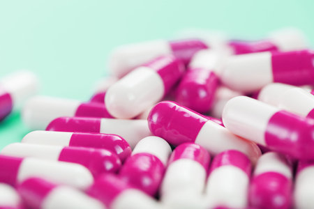 Pink medical pills on a black background. Top view as a full-screen texture background.