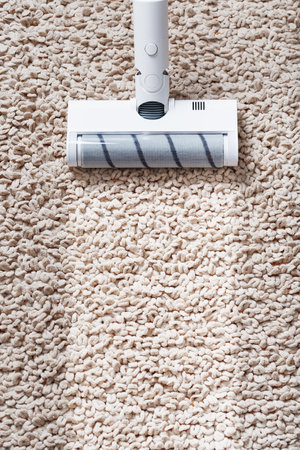 The turbo brush of a cordless vacuum cleaner cleans the carpet in the house in close-up. Modern...