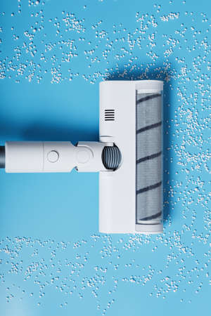 A white vacuum cleaner cleans the blue background from debris from white balls. Top view, free spaceの写真素材