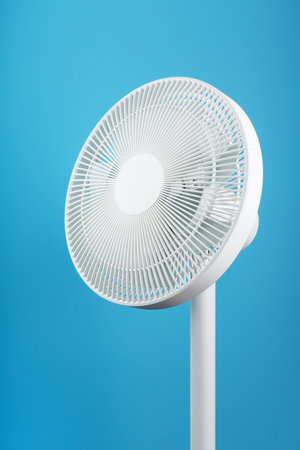 A high-tech white electric fan with a modern design for cooling the room on a blue backgroundの写真素材