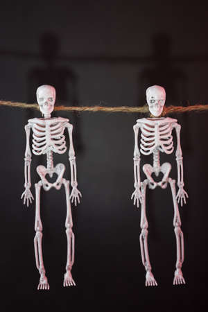 Skeletons hang on a rope on a black background with red illumination. Happy Halloween holiday.の写真素材