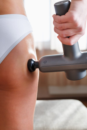 Self-massage of the female buttock with a percussion massage gun at home. Shock massage to restore...