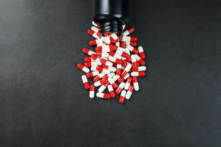 A scattering of Red and white capsules on a black background. Top view Free spaceの写真素材
