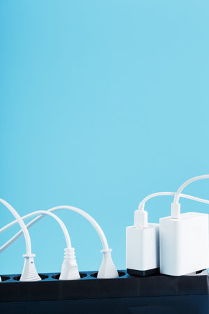 Surge protector with connected white wires of electrical appliances on a blue background. Free space