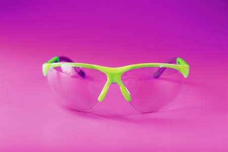 Protective open glasses isolated on a pink background. Reliable eye protection, free spaceの写真素材