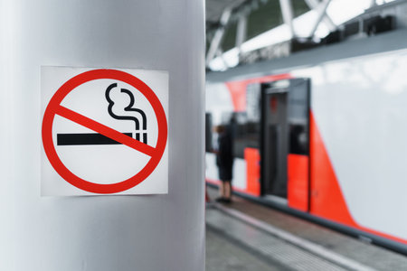 A sign prohibiting smoking on a pole near the railway platform. Smoking in public places is...