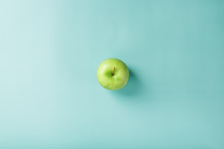 One green apple on a green background with a minimalistic composition. Top view, free spaceの写真素材