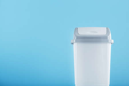 White trash can on a light blue background with free space. Cleanliness, order and segregated waste collection conceptの写真素材