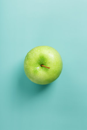 One green apple on a green background with a minimalistic composition. Top view, free spaceの写真素材