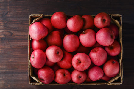 Red apples in a box on a wooden table, top view. Healthy organic fruitsの写真素材