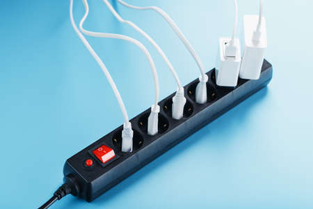 Surge protector with connected white wires of electrical appliances on a blue background. Free spaceの写真素材