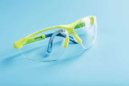 Technological protective green glasses isolated on a blue background. Reliable eye protection, free spaceの写真素材