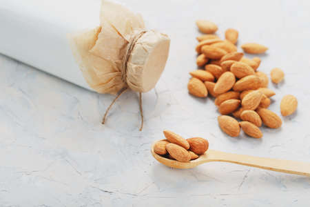 Almond milk in a bottle with a handful of seeds and a wooden spoon on a light background. Top viewの写真素材