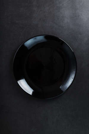 Black plate on a black background top view. Minimalistic conceptの写真素材