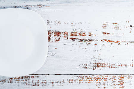 An empty round white plate on a blue wooden table. Top viewの写真素材