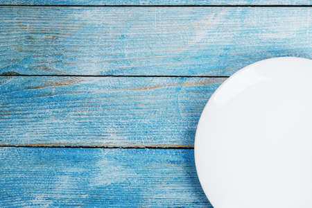 Empty round bowl on a blue wooden background from above. Free spaceの写真素材