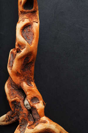 Textured curved Wooden snag of brown color with texture on a black background. Decorative wooden element, close-up, minimalism.の写真素材