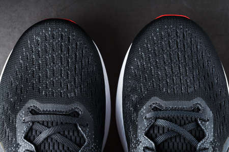 Black running shoes with mesh and black laces close-up on a dark background. Top view of sports sneakers.の写真素材