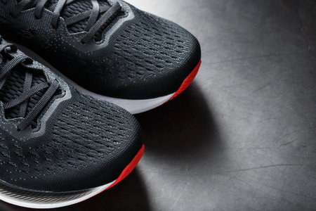 Black sports sneakers with red soles on a black background. Free space
